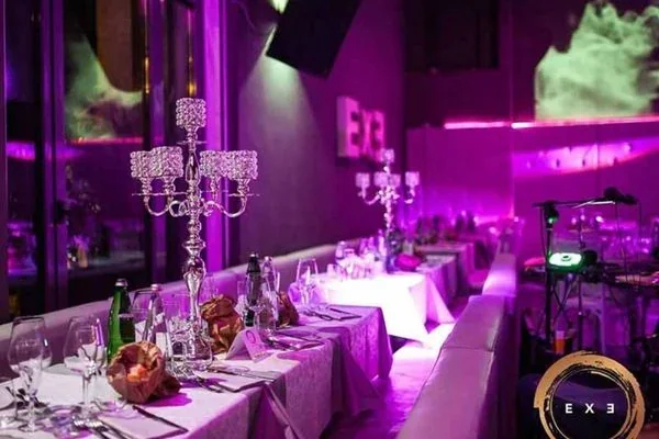 Sala dell’Exe Roma allestita per la cena con tavoli lunghi e candelabri